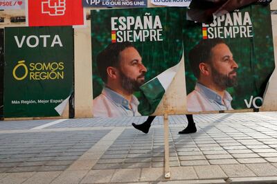 A woman walks past banners of Spain's far-right Vox party candidate Santiago Abascal in Torre-Pacheco, Spain, Monday, Nov. 11, 2019. The farming town of Torre-Pacheco, heavily reliant on foreign workers, voted in droves for Vox, which has vowed to build walls to contain migrants and prioritize the needs of Spaniards. (AP Photo/Sergio Rodrigo)
