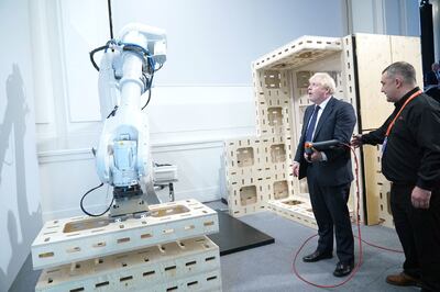 Boris Johnson operates a robotic arm in the Innovation Zone, during the Global Investment Summit in London. AFP