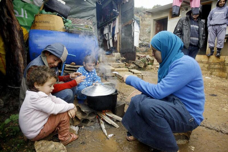 A Syrian refugee and her children prepare food in the Chouf mountain town of Ketermaya, Lebanon. The U.N. World Food Program says it has suspended a food voucher program serving more than 1.7 million Syrian refugees because of a funding crisis. (AP Photo/Mohammed Zaatari, File)