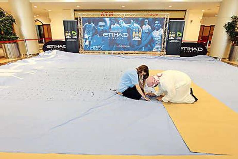 A man signs the world's largest Manchester City FC shirt at Khalidiya Mall in Abu Dhabi yesterday. The shirt has already been signed by 2,000 supporters.
