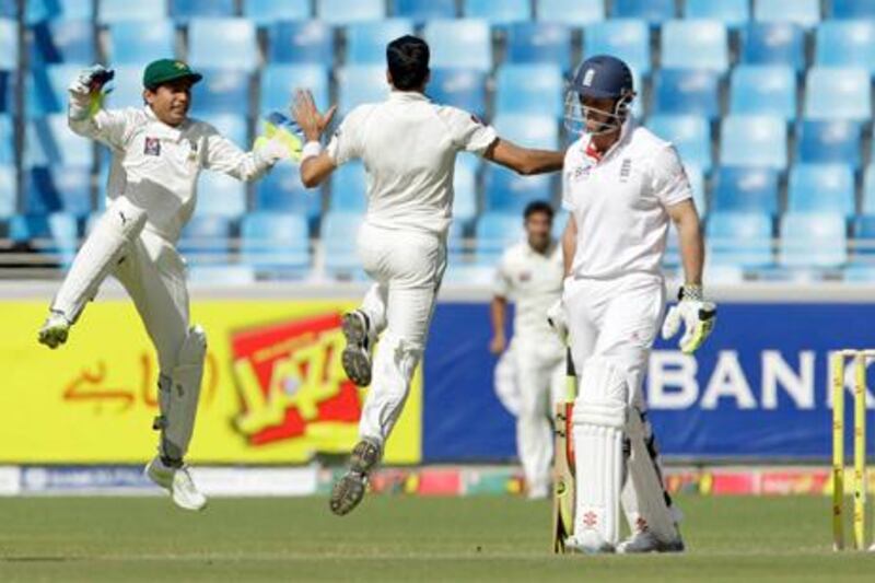 Pakistan's Umar Gul, center, celebrates taking the wicket of England's captain Andrew Strauss, right, with wicketkeeper Adnan Akmal during the third day of the first cricket test match of a three match series between England and Pakistan at the Dubai International Cricket Stadium in Dubai, United Arab Emirates, Thursday, Jan. 19, 2012.  (AP Photo/Matt Dunham)