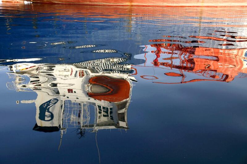 The superstructure of a ship lies reflected in the water in Elefsina Bay, Elefsina, Greece. By midyear, Opec and IEA forecasts suggest excess inventory on the order of 400 million barrels, enough to fill 200 supertankers. Kostas Tsironis / Bloomberg