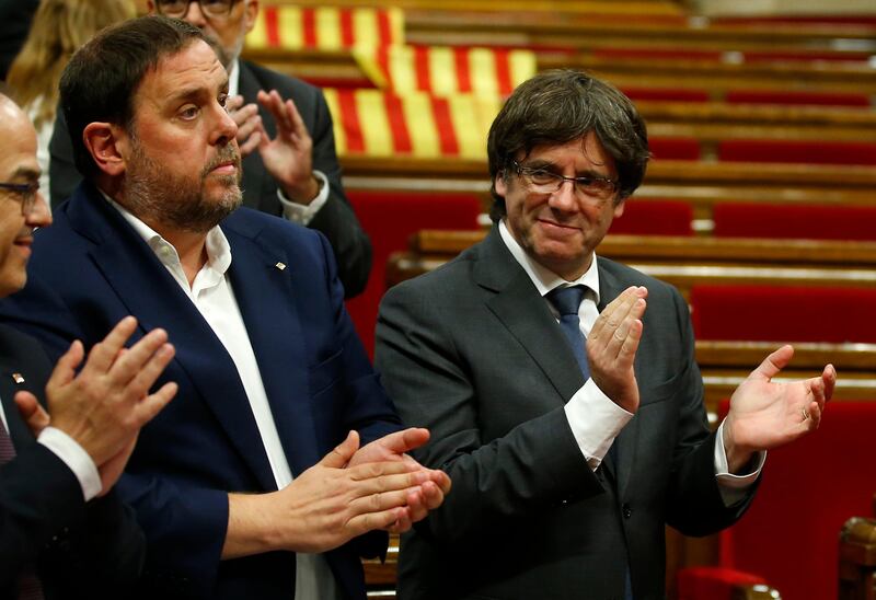 Catalonia regional President Carles Puigdemont, right, applauds next to vice-president Oriol Junqueras, left, after the voting during a plenary session at the Parliament of Catalonia in Barcelona, Spain, Wednesday, Sept. 6, 2017. Catalan lawmakers are voting on a bill that will allow regional authorities to officially call an Oct. 1 referendum on a split from Spain, making concrete a years-long defiance of central authorities, who see the vote as illegal. (AP Photo/Manu Fernandez)