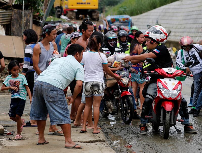 Motorcycle riders distribute bag of goods to residents. EPA