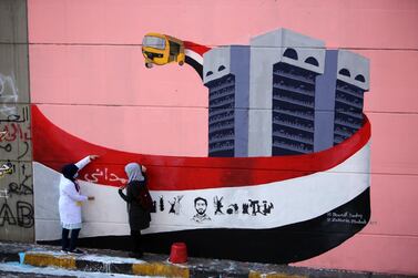 Iraqi demonstrators rest in front of a mural painting in Tahrir square during ongoing anti-government demonstrations in Baghdad. AFP