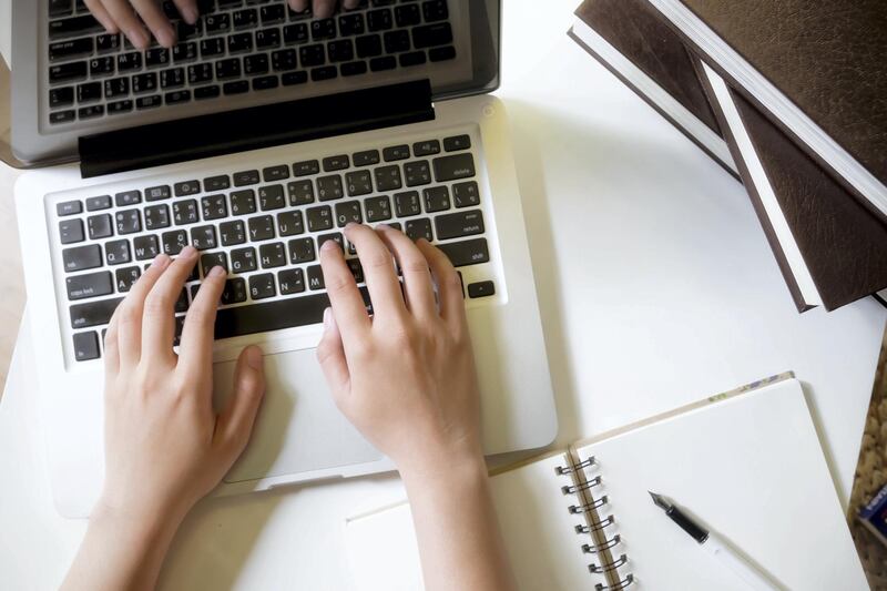 Top view of woman's hands working with laptop on white table. Education concept.