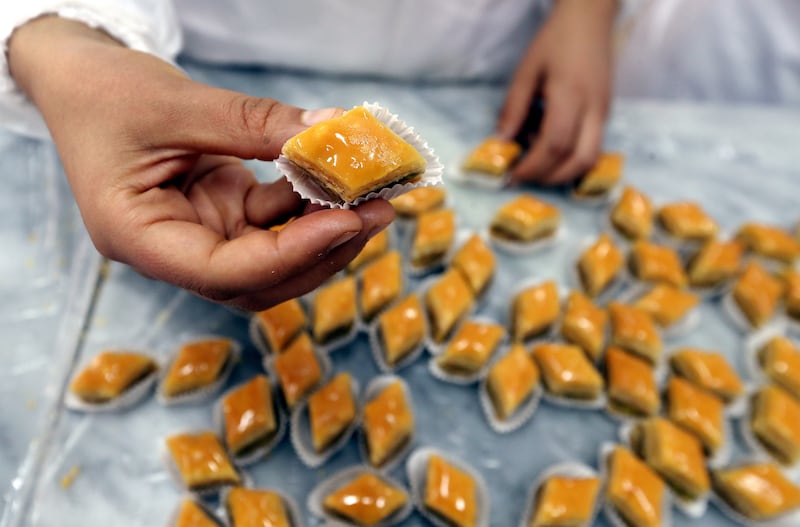 A Tunisian woman shows a type of pastry made at the pattiserie.