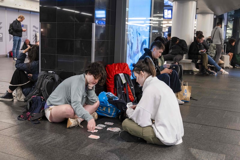 Travellers play cards as they wait for their train at Amsterdam Central Station. AFP