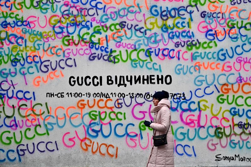 A Gucci shop window covered with protective chipboard against fragments of shelling, with a sign reading 'Gucci is open', in the centre of Ukrainian capital, Kyiv. AFP