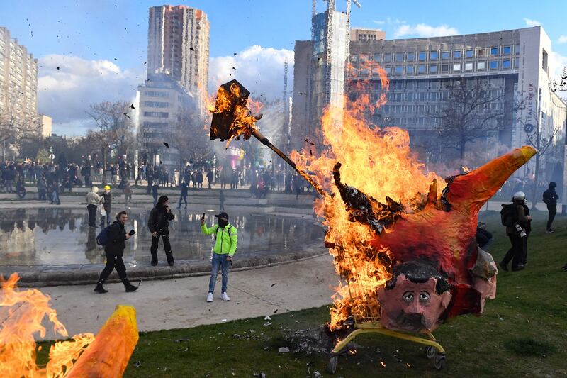 Protesters burn an effigy of French President Emmanuel Macron during a demonstration at Place d'Italie, Paris, after the government pushed for pension reforms without a vote. AFP