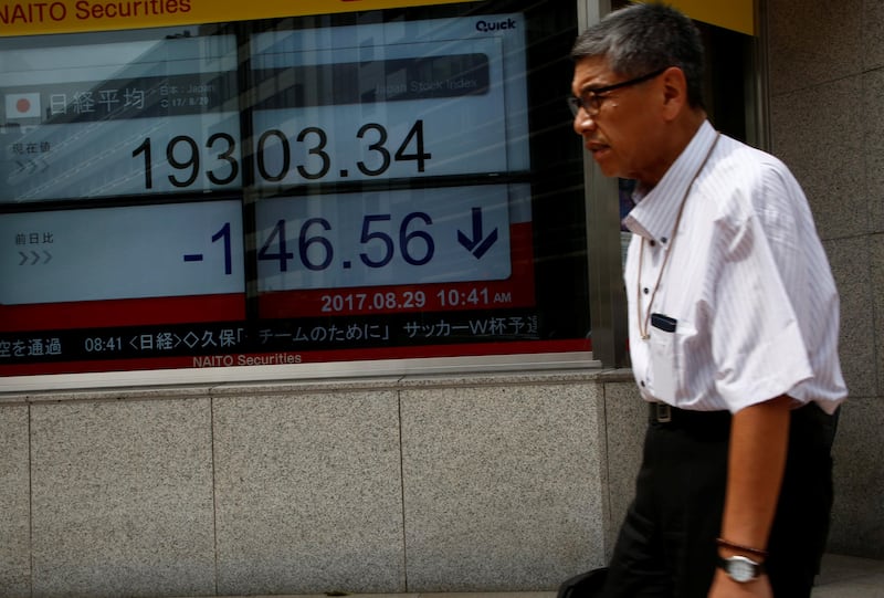 A man walks past an electronic board showing Japan's Nikkei average outside a brokerage at a business district in Tokyo, Japan, August 29, 2017.   REUTERS/Kim Kyung-Hoon