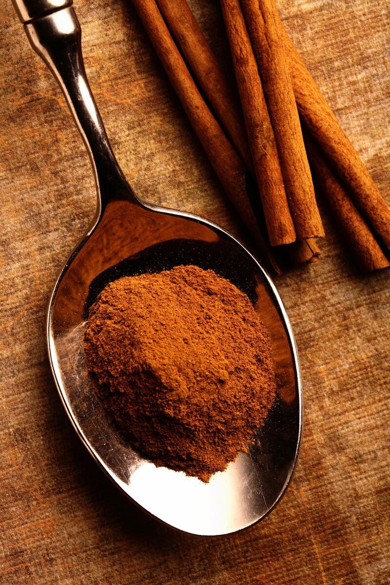 Spoon full of powdered cinnamon, with cinnamon sticks beside, on a light patterned ground.Credit: iStockphoto.com