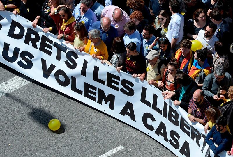 Protesters walk behind a banner reading 'In favour of rights and freedoms. We want you at home', referring to the jailed separatist leaders. AFP/Josep LAGO