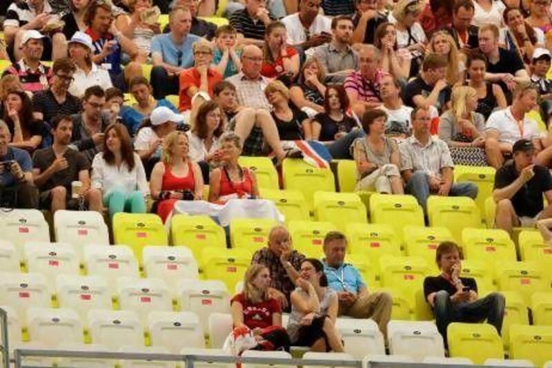 Spectators sit behind rows of empty seats for officials and sponsors at the swimming heats at the Aquatics Centre in the London Olympic Park.