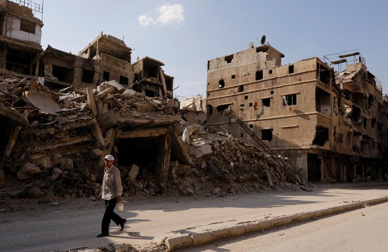 A resident walks along a damaged street in Yarmouk, a Palestinian camp in Damascus, Syria. REUTERS