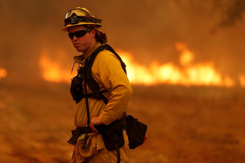 A firefighter stands near a grass fire as he prepares to defend a home from the Detwiler fire in Mariposa, California. Stephen Lam / Reuters
