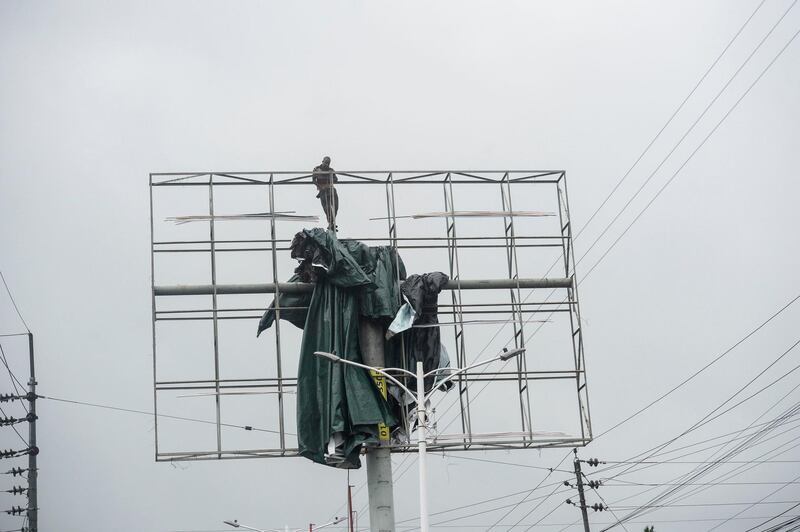 A worker removes a tarpaulin from an advertising structure ahead of the expected landfall of cyclone Amphan, in Khulna.  AFP