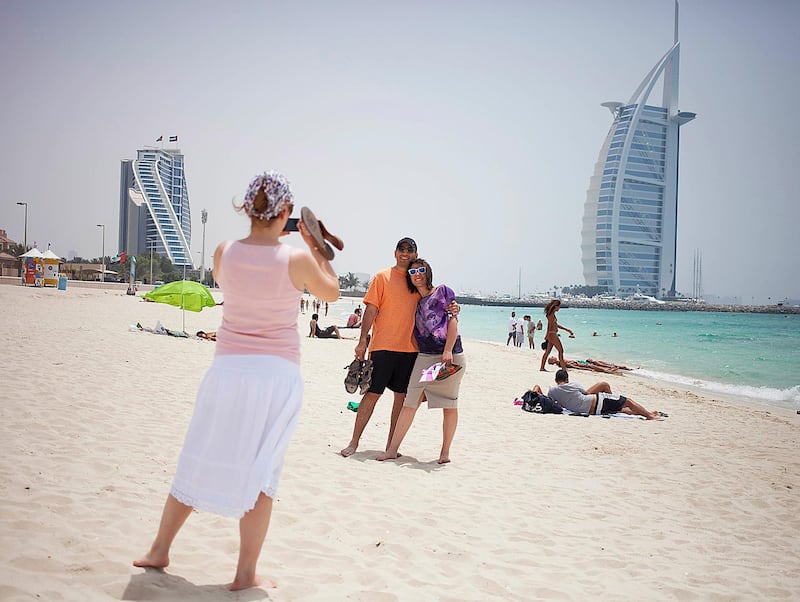 Dubai, United Arab Emirates - May 23 2013 - Tourists from Turkey take pictures at the public beach by Burj Al Arab after being dropped off there by a tour bus. STOCK. (Razan Alzayani / The National)  