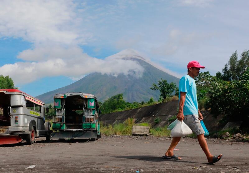 A villager walks as the Mayon volcano spews ashes and lava in Legaspi city.  EPA
