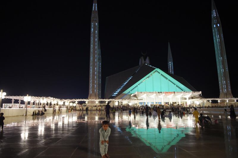 A child joins Pakistani Muslim worshipers as they gather at the illuminated Grand Faisal Mosque in Islamabad. AFP