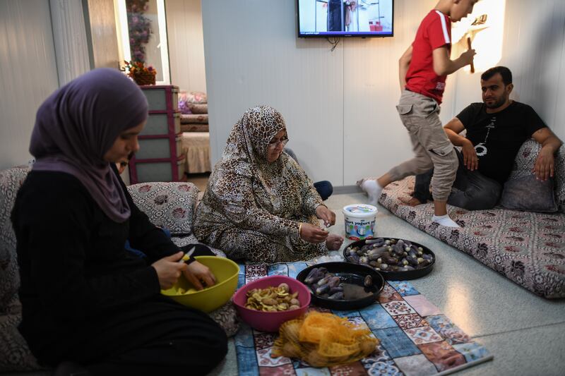 Rasha Yousuf, centre, and Affat Iskendro, left, prepare vegetables to make pickles in their home at the camp. Getty Images