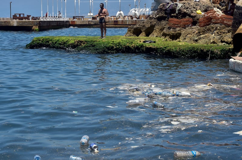 A fisherman stands on a little rock island near debris and plastic waste dumped in the Mediterranean Sea in Beirut. A new UN report says that plastic pollution can be cut by 80 per cent by 2040, if action is taken now to reuse, recycle and diversify away from plastics.  EPA 