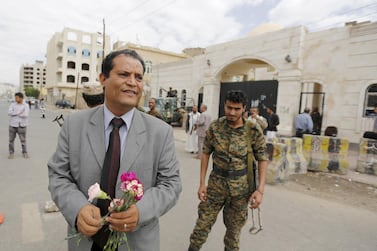 The spokesperson for the Baha'i community in Yemen, Abdullah Al Olufi, holds flowers as he stands outside a state security court during a hearing in the case of a Baha'i man charged with seeking to establish a base for the community in Yemen, in the country's capital Sanaa on April 3, 2016. Reuters. 