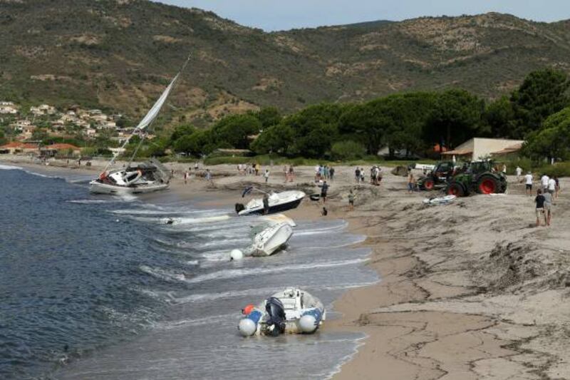 People stand on a beach in Coggia, Corsica, where boats lie on the shore. Getty Images