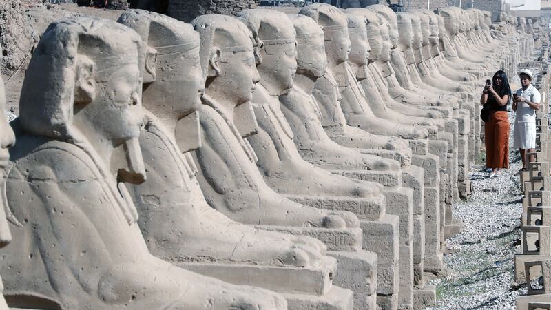 People stand at the Avenue of Sphinxes.