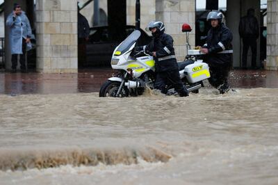 Traffic policemen push a motorcycle through a flooded street during heavy rains in Amman, Jordan, February 28, 2019. REUTERS/Muhammad Hamed