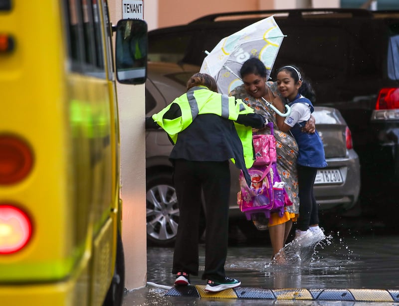 A pupil gets carried to her school bus on 
a rainy morning at Khalifa City in Abu Dhabi on Tuesday morning. Photos: Victor Besa / The National