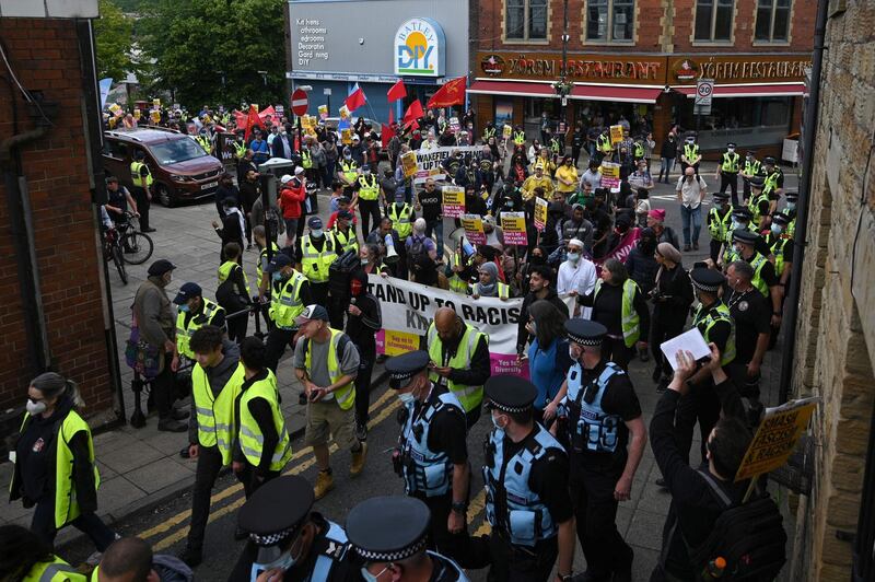 Police officers monitor anti-fascist demonstrators as they set off on a march in Batley, West Yorkshire. AFP