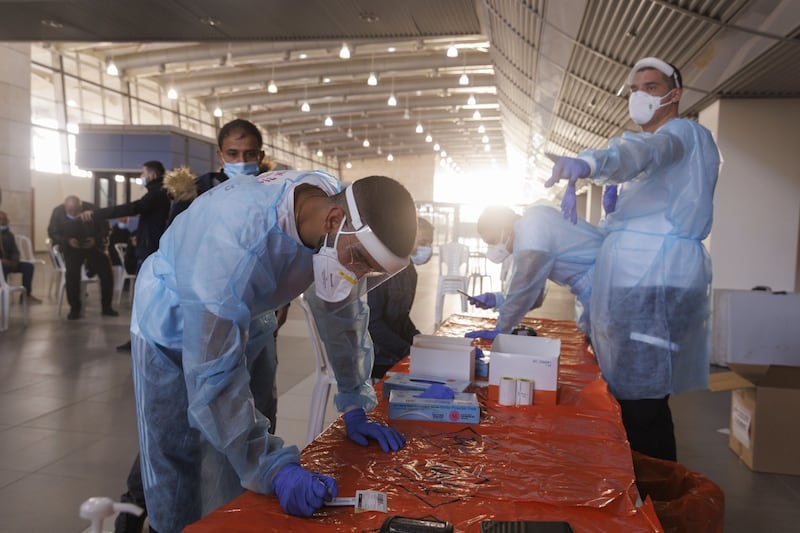 Medical workers conduct Covid-19 antigen tests on Palestinians entering Israel from the Gaza Strip. Bloomberg