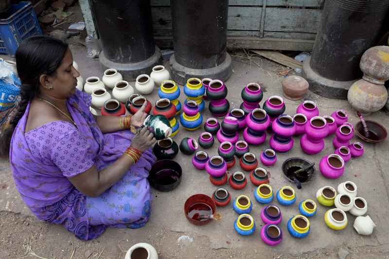 A street vendor applies dye to earthen pots to be used as decorative items, in Hyderabad. AFP