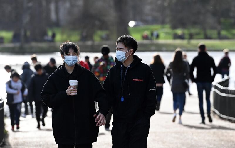 People wear face masks as they walk through a park in London. EPA
