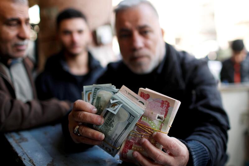 A man holds money as he poses for a picture at a foreign currency exchange market in Baghdad. Reuters
