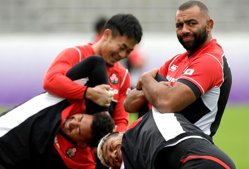 Japan captain Michael Leitch, top right, stretches teammate Lomano Lava Lemeki during a training session in Tokyo, Japan, Thursday, Oct. 17, 2019. Japan play South Africa in a Rugby World Cup quarterfinal on Sunday Oct. 20. (AP Photo/Mark Baker)