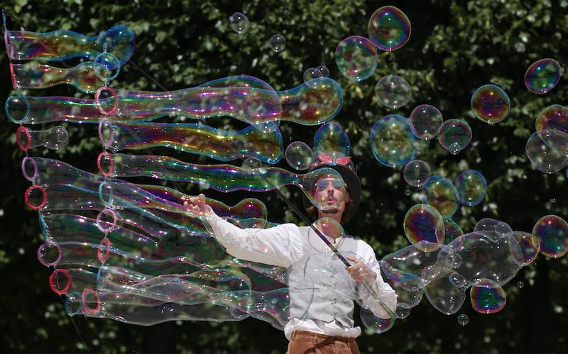 A street artist blows bubbles during a performance in Paris, as a heatwave sweeps across much of France and Europe. AFP
