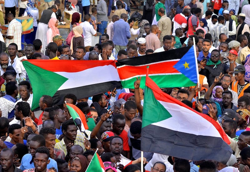 Sudanese demonstrators display their national flag and the national flag of South Sudan, as they attend a sit-in protest outside the Defence Ministry in Khartoum. Reuters