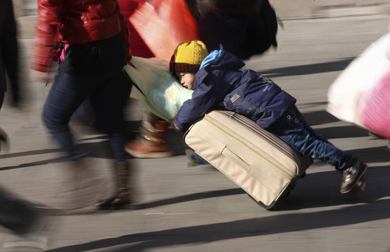 A person drags a suitcase and child at a railway station in Qingdao, Shandong province, on January 28, 2014, ahead of the Chinese Lunar New Year. The Year of the Horse begins January 31. About 3.62 billion trips will be made during the 40-day Spring Festival travel rush, which began January 16, according to the government. China Daily / Reuters photo