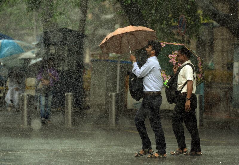 TOPSHOT - Indian pedestrians carry unbrellas as they walk through heavy rain showers in Mumbai on July 13, 2017.  / AFP PHOTO / PUNIT PARANJPE