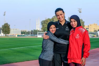 Hamda Al Hosani, right, is an inspiration to young athletes like Mouza Al Hamed, left, and even her coaches, like Naila Khemis, centre. Victor Besa / The National