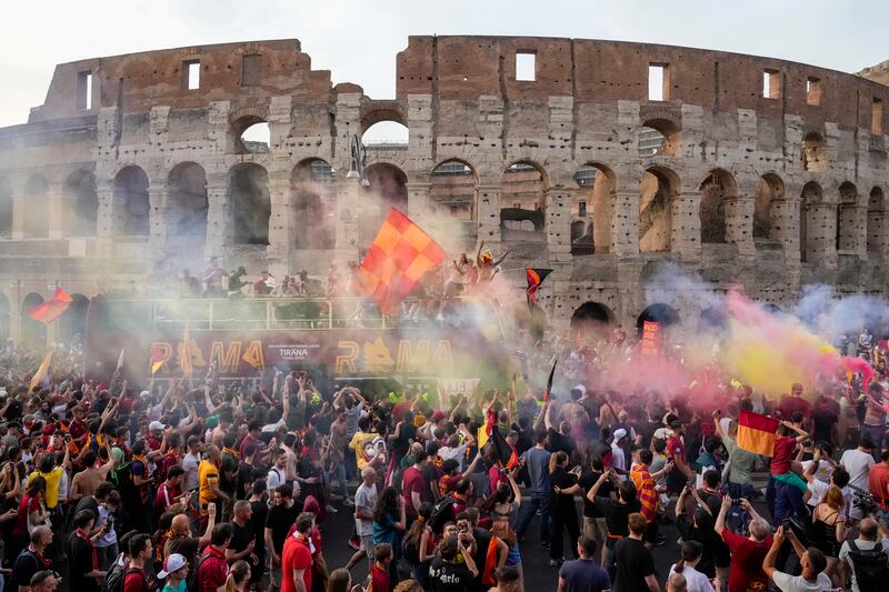 The bus with the AS Roma soccer team drives amid a crowd of jubilant supporters, in front of the Colosseum in Rome, Thursday, May 26, 2022, during the celebration for their victory in the Europe Conference League soccer final against Feyenoord in Tirana on Wednesday.  (AP Photo / Gregorio Borgia)