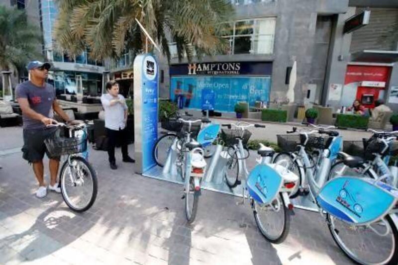 Abdulaziz Abdullah, left, executive manager of Byky, and Miroslaw Szibas, of NextBike, demonstrate how to use a bicycle rental station, which can be found at key sites such as Burj Khalifa and Marina Mall. Sarah Dea/The National