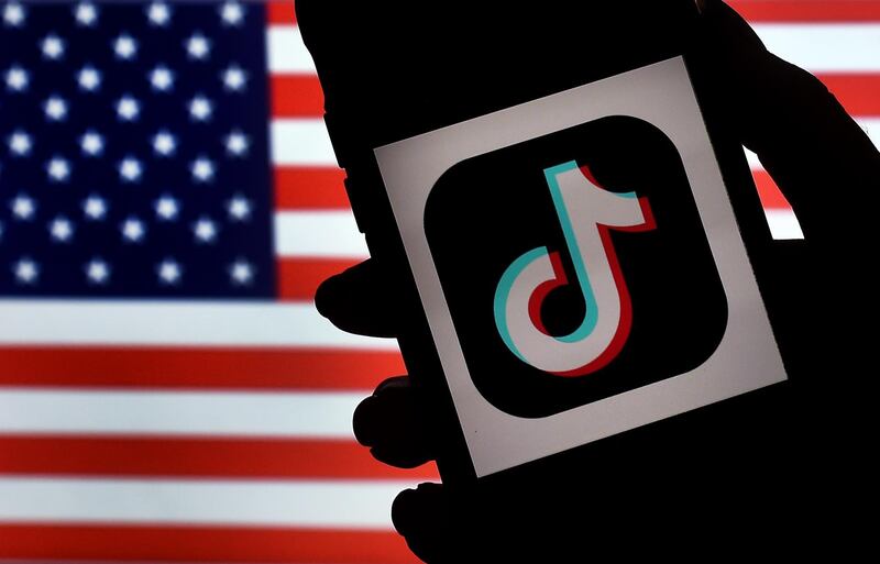 (FILES) In this file illustration photo taken on August 3, 2020  the social media application logo TikTok is displayed on the screen of an iPhone on an American flag background in Arlington, Virginia.  The US is expanding its China-targeted Clean Network program to include Chinese-made cellphone apps and cloud computing services that it claims are security risks, Secretary of State Mike Pompeo announced on August 5, 2020. / AFP / Olivier DOULIERY
