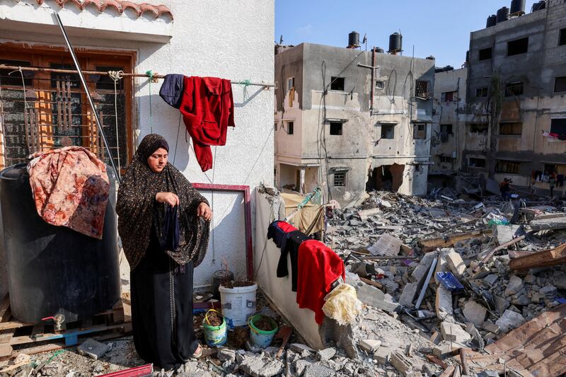 A Palestinian woman hangs laundry at her house that was damaged during Israel-Gaza fighting, as ceasefire the holds in Gaza city. Reuters