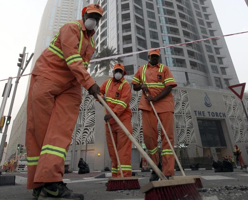 Workers clean in front of the Torch skyscraper. EPA 