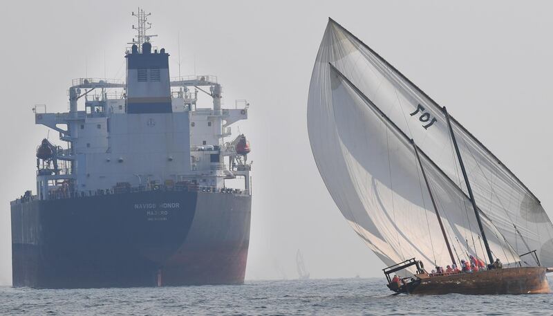 TOPSHOT - Emirati competitors sail their dhow past a crude oil tanker Navig8 Honor during the Dalma Sailing Festival in the waters of Dalma island in the Gulf, about 40 kms off of the Emirati capital Abu Dhabi, on October 22, 2019.  / AFP / KARIM SAHIB
