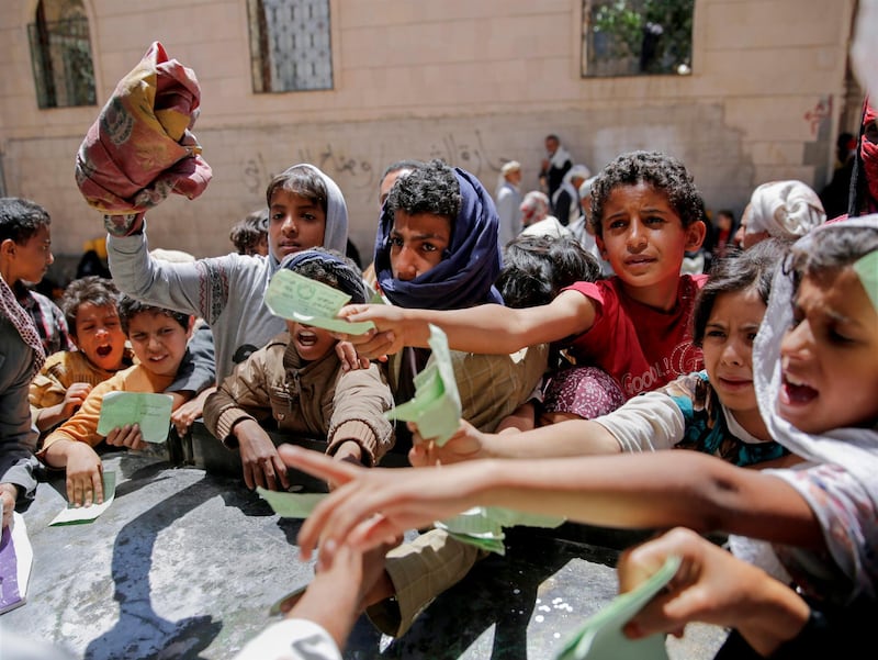 FILE - In this April 13, 2017, file photo, Yemenis present documents in order to receive food rations provided by a local charity, in Sanaa, Yemen. Saudi Arabia said Sunday, Jan. 21, 2018 that the coalition it is leading in Yemen will provide $1.5 billion in new humanitarian aid for international relief organizations working in the impoverished country. It comes as aid groups say coalition airstrikes are destroying critical infrastructure and that the coalition needs to do more to facilitate the delivery of fuel, food and medicine at Yemeni ports. (AP Photo/Hani Mohammed, File)