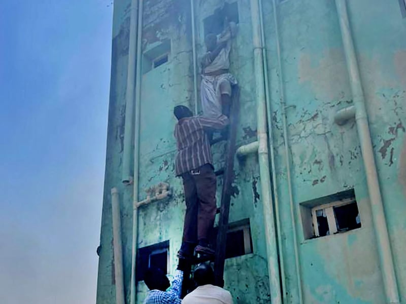 People assist others climbing a ladder evacuating a burning building in the wake of clashes in Sudan's eastern city of Kassala, close to the border with Eritrea (Photo by AFP)